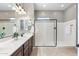 Bright bathroom featuring double vanity, walk-in shower with glass enclosure, and neutral tile flooring at 2215 E La Costa Dr, Gilbert, AZ 85298