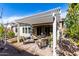 Covered back patio with outdoor furniture surrounded by beautiful plants and well-maintained landscaping at 25913 W Sands Dr, Buckeye, AZ 85396