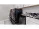 Efficient laundry room with black washer and dryer, marble counter, and sleek white cabinets at 25913 W Sands Dr, Buckeye, AZ 85396