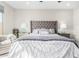 Well-lit main bedroom featuring a plush bed with a tufted headboard, side tables, and two lamps at 25913 W Sands Dr, Buckeye, AZ 85396