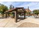 Shaded picnic area with tables and seating near a community splash pad and playground at 25913 W Sands Dr, Buckeye, AZ 85396