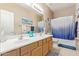 Bright bathroom featuring a double sink vanity and tub with blue gradient shower curtain at 2605 N 115Th Dr, Avondale, AZ 85392