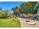 Serene backyard with lush lawn, shade trees, a cozy hammock, and a charming fire pit area at 2919 W Kerry Ln, Phoenix, AZ 85027