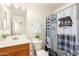 This bathroom features a single sink vanity with wood cabinets and a shower with themed curtain at 2977 W Mira Dr, San Tan Valley, AZ 85144