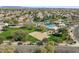 An aerial view showcases a community pool, sand volleyball court, and lush green spaces in a residential area at 3551 E Shannon St, Gilbert, AZ 85295