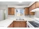 Close up of kitchen area featuring white appliances, laminate countertops, wood cabinets and double stainless sink at 3614 W Georgia Ave, Phoenix, AZ 85019