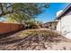 Wide view of the backyard with a grassy area, stone, mature trees, and a backyard wall at 3927 W Phelps Rd, Phoenix, AZ 85053