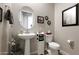 Stylish half bathroom featuring a pedestal sink, decorative mirror, and neutral color scheme at 42024 W Rosewood Ln, Maricopa, AZ 85138