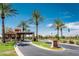 Welcoming community entrance with palm trees, landscaping, and a clear blue sky at 42024 W Rosewood Ln, Maricopa, AZ 85138