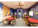 Bright game room featuring round tables, comfortable chairs, a ceiling fan, and a television for entertainment at 42024 W Rosewood Ln, Maricopa, AZ 85138