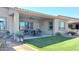 Covered patio with an outdoor dining area, lush landscaping, and exterior lighting at 42024 W Rosewood Ln, Maricopa, AZ 85138