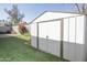 View of a backyard featuring artificial grass, flowering bushes, a block wall, and a storage shed at 4428 W Mission Ln, Glendale, AZ 85302