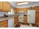 Traditional kitchen with wooden cabinets, white appliances, and tile flooring at 4428 W Mission Ln, Glendale, AZ 85302