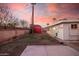 A backyard with a small concrete patio, a red storage shed, and wood fencing at sunset at 4502 N 2Nd Dr, Phoenix, AZ 85013