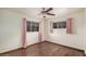 A bedroom with two windows dressed with pink drapes and hardwood floors, illuminated by a ceiling fan at 4502 N 2Nd Dr, Phoenix, AZ 85013