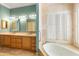 This bathroom features double sinks, granite countertops, mirrors and modern lighting, with a bathtub near shuttered windows at 5345 E Mercer Ln, Scottsdale, AZ 85254