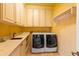 Functional laundry room with ample counter space, storage cabinets, sink, and modern appliances at 5345 E Mercer Ln, Scottsdale, AZ 85254