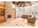 Living room with a stone fireplace, travertine floors, and a vaulted wood beam ceiling at 5345 E Mercer Ln, Scottsdale, AZ 85254