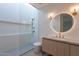 Modern bathroom featuring a walk-in shower, wood cabinet vanity, and a round mirror with accent lighting at 5910 N 45Th St, Phoenix, AZ 85018