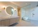 Luxurious bathroom with an illuminated round mirror, dual sconces, and a glass-enclosed shower with a soaking tub at 5910 N 45Th St, Phoenix, AZ 85018