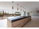 Modern kitchen island with stone countertop, wood cabinets, pendant lights, and expansive windows to the backyard at 5910 N 45Th St, Phoenix, AZ 85018