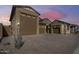 Exterior view of home featuring multiple garages and desert landscaping under a vibrant dusk sky at 7694 W Desert Spoon Dr, Peoria, AZ 85383