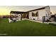 Inviting backyard oasis featuring a covered patio, artificial grass, and desert-themed mural for outdoor entertaining at 8009 W Northview Ave, Glendale, AZ 85303