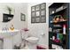 Stylish powder room with a pedestal sink, charming decor, and unique black storage shelving at 8009 W Northview Ave, Glendale, AZ 85303