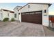 Exterior view of a two-story home featuring a brick driveway, a two-car garage, and desert landscaping at 8009 W Northview Ave, Glendale, AZ 85303