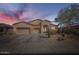 Charming, one-story stucco home featuring a three-car garage and desert landscaping at sunset at 9590 W Bajada Rd, Peoria, AZ 85383