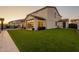 Lush backyard with a well-manicured lawn, mature trees, and a modern glass garage door feature on the house at 9937 E Harvest Rd, Florence, AZ 85132