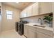 This laundry room has lots of cabinets for storage, as well as a modern washer and dryer at 9937 E Harvest Rd, Florence, AZ 85132