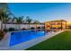 Backyard pool with lush landscaping features an outdoor kitchen area under a stylish pergola with string lights at 9937 E Harvest Rd, Florence, AZ 85132