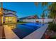 Backyard pool is illuminated, surrounded by lush landscaping and artificial turf, complemented by a covered patio at 9937 E Harvest Rd, Florence, AZ 85132