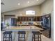 Kitchen with stainless steel appliances, dark brown cabinets, granite countertops, tile flooring, and a kitchen island with seating at 11538 W Laurelwood Ln, Avondale, AZ 85392