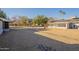 Expansive gravel front yard featuring mature trees, solar panels and a charming sunroom, creating a welcoming outdoor space at 12946 W Maplewood Dr, Sun City West, AZ 85375