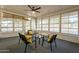 Enclosed sunroom with four chairs, a glass table and many windows creating an airy space at 12946 W Maplewood Dr, Sun City West, AZ 85375
