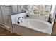 Bathroom featuring a white soaking tub, black fixtures, a window, and stylish marble-look tile at 1302 E Voltaire Ave, Phoenix, AZ 85022