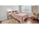 Bedroom featuring a bed with a pink quilt, hardwood floors, and a window at 13534 W Young St, Surprise, AZ 85374