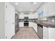 Well-lit kitchen features stainless appliances, tiled backsplash, white cabinets, and durable tile flooring at 13534 W Young St, Surprise, AZ 85374