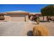 Garage and covered entry to a tan home featuring desert landscaping and a tiled roof at 16016 W Indigo Ln, Surprise, AZ 85374