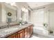 Bathroom featuring double sinks, granite counters, and soaking tub under bright window at 16601 S 16Th Dr, Phoenix, AZ 85045