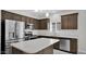 Stylish kitchen with stainless steel appliances, island, dark wood cabinets, and tile flooring at 2296 S 235Th Dr, Buckeye, AZ 85326