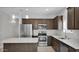 Modern kitchen with stainless steel appliances, an island, dark wood cabinets, and a tile floor at 2296 S 235Th Dr, Buckeye, AZ 85326