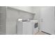 Bright laundry room featuring a modern washer and dryer, built in shelf, and a door at 2296 S 235Th Dr, Buckeye, AZ 85326