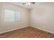 Neutral bedroom features wood floors, a ceiling fan, and a window with natural lighting at 2521 W Mark Ln, Phoenix, AZ 85085