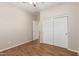 Neutral bedroom features wood floors, a ceiling fan, closet and a view of the hallway at 2521 W Mark Ln, Phoenix, AZ 85085