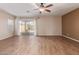 Bright living room with wood-look tile floors, a ceiling fan, and a sliding glass door leading to the backyard at 2521 W Mark Ln, Phoenix, AZ 85085