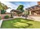 Spacious backyard with artificial turf, outdoor kitchen, fireplace and pergola-covered seating area at 2799 E Jade Pl, Chandler, AZ 85286