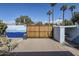 Secured back yard with a tall privacy fence, a sliding wood gate, and mature palm trees in the background at 3015 N 8Th Ave, Phoenix, AZ 85013